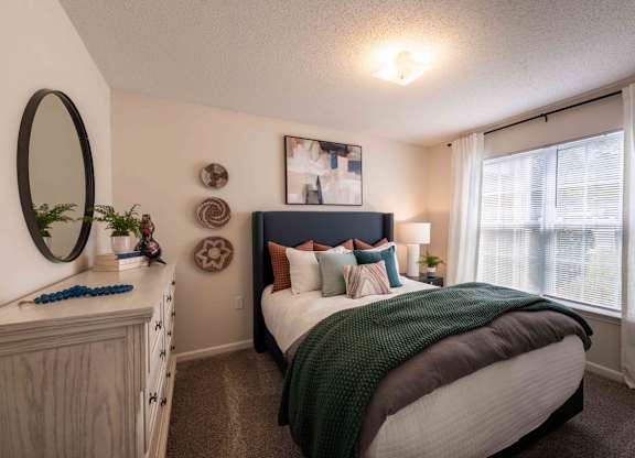 A bedroom with a bed, dresser, and window.