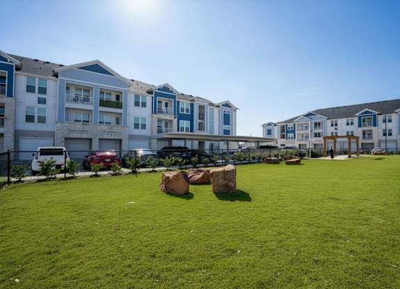 A sunny day at a grassy field with apartment buildings in the background.