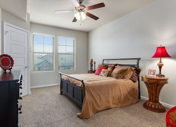 A bedroom with a bed, a dresser, and a ceiling fan.