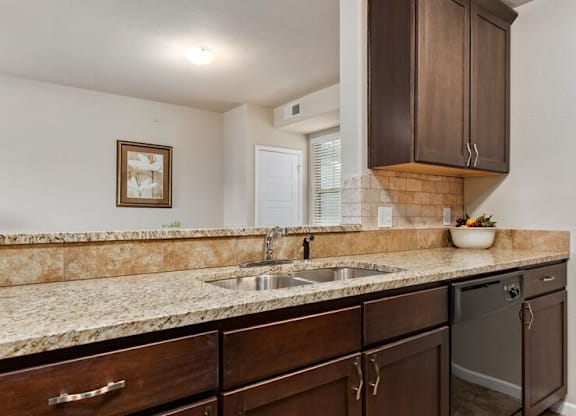 A kitchen with brown cabinets and a marble countertop.