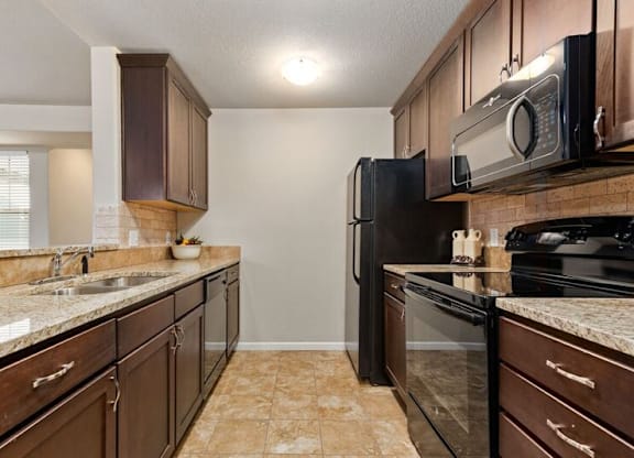 A kitchen with brown cabinets and black appliances.