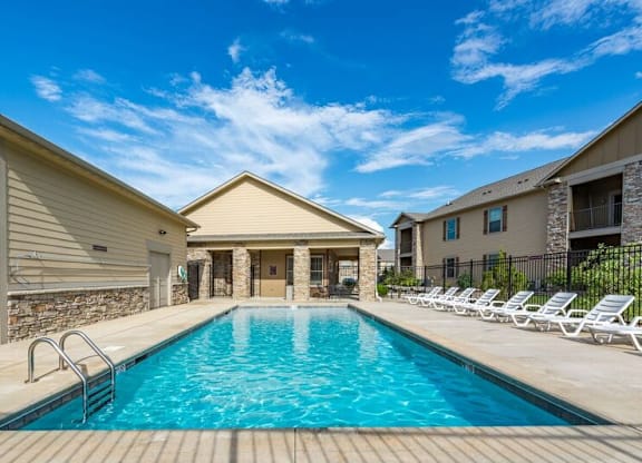 A swimming pool surrounded by sun loungers and a stone wall.