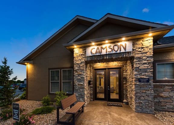 The image shows the front of a building named CAMSON with a bench in front of it.