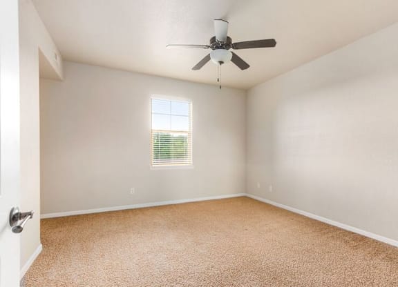 A room with a ceiling fan and a window with blinds.