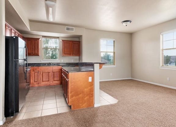 A kitchen with brown cabinets and a black refrigerator.