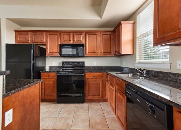 A kitchen with black appliances and brown wooden cabinets.