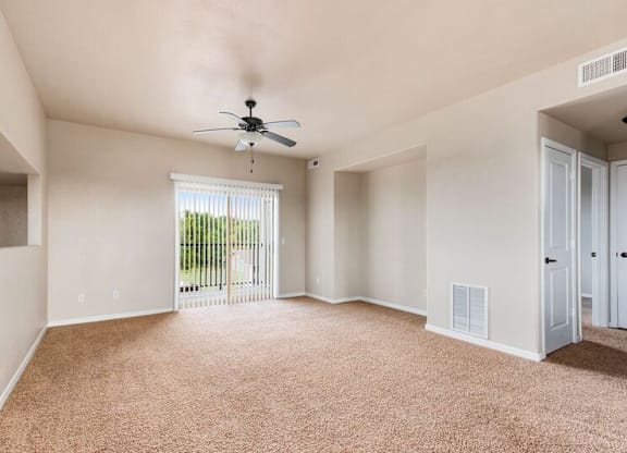 A room with a ceiling fan and carpeted floor.