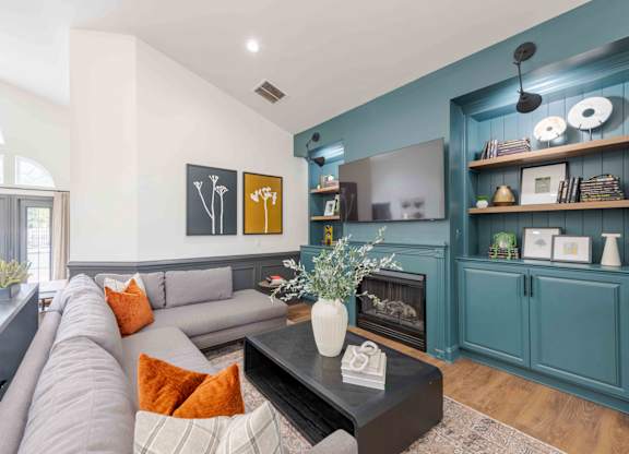 A living room with a grey couch and a fireplace.