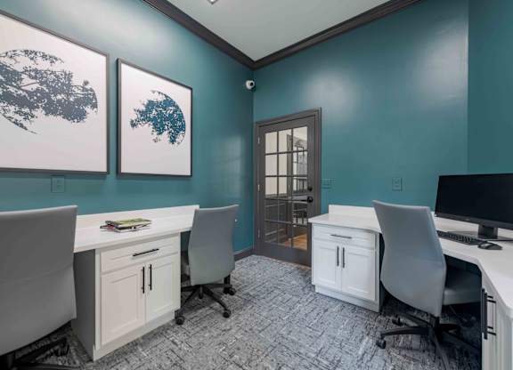 A room with two desks and chairs, a cabinet, and two framed pictures on the wall.