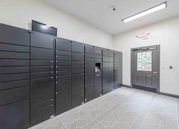 A room with a wall of lockers and a door with a window.