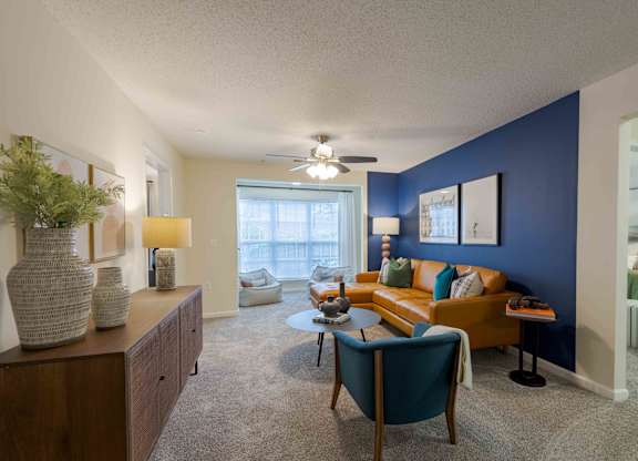 A living room with a blue accent wall and a ceiling fan.