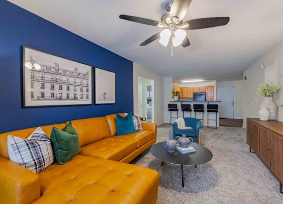 A living room with a yellow couch and a ceiling fan.