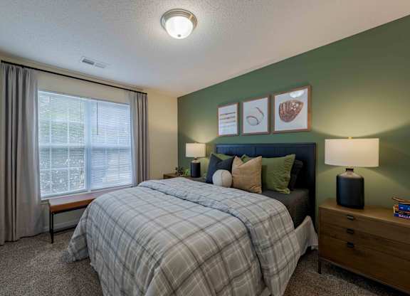 A bedroom with a bed, nightstand, and window.