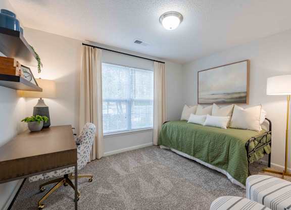 A bedroom with a bed, desk, and chair.