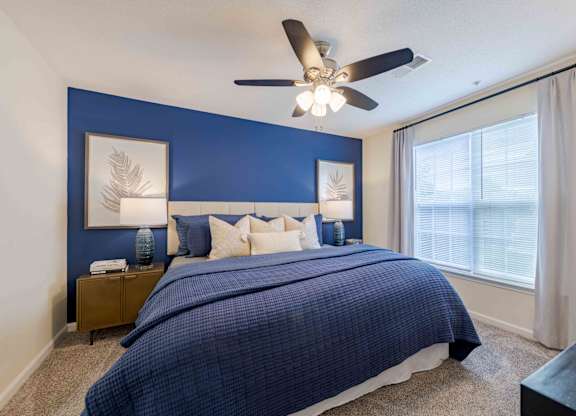 A bedroom with a bed, nightstands, and a ceiling fan.