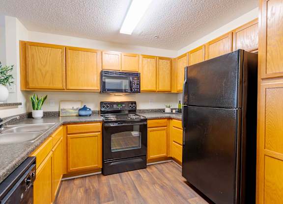 A kitchen with wooden cabinets and black appliances.