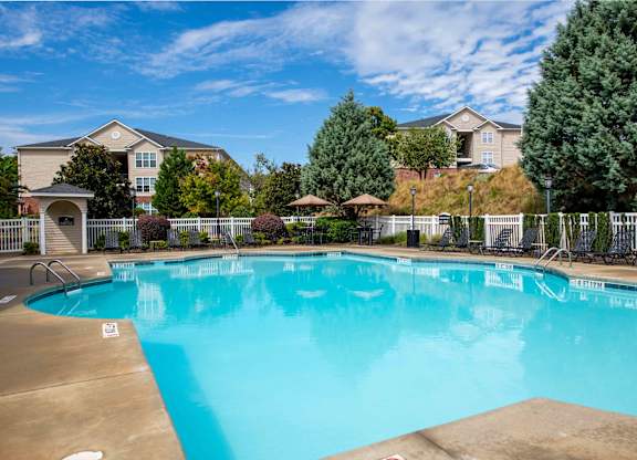 A large swimming pool in front of a building with a fence around it.