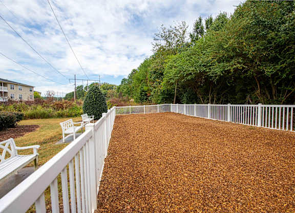 A white fence borders a brown gravel area.