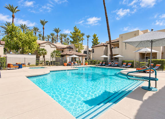 A large swimming pool surrounded by palm trees and lounge chairs.