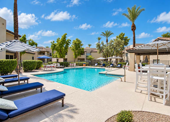 A pool area with sun loungers and a shaded table.