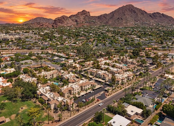A sunset view of a residential area with houses and palm trees.