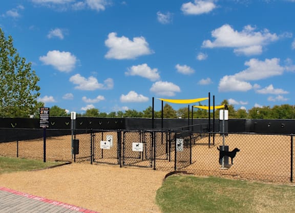 A dog park with a yellow canopy and a black fence.