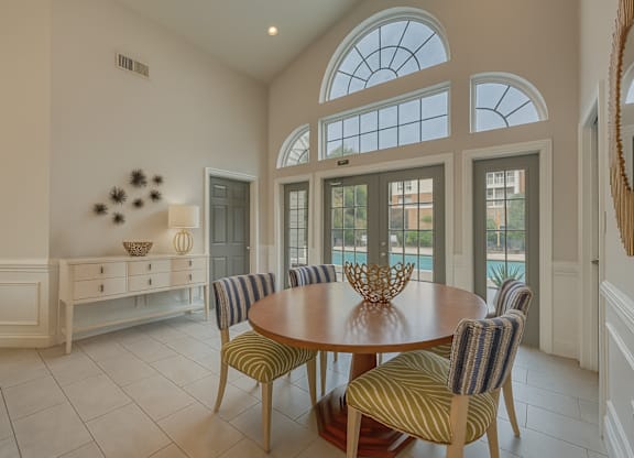 A dining room with a round table and striped chairs.