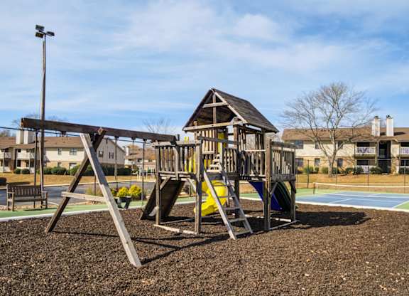 A playground with a swing set and a yellow slide.