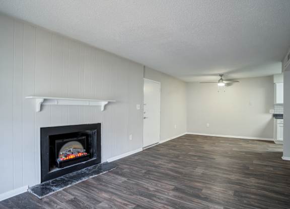 A room with a fireplace and wood flooring.