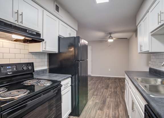 A kitchen with black appliances and white cabinets.