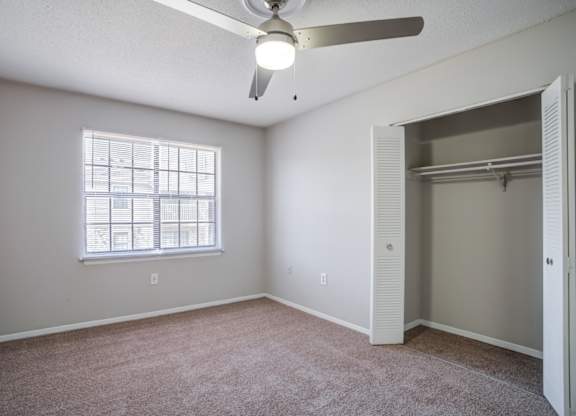 A room with a ceiling fan and a window with blinds.