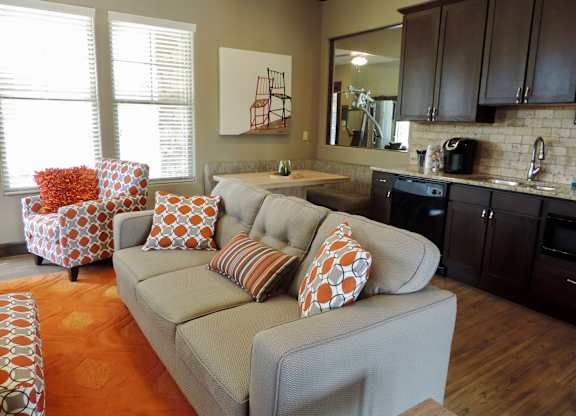 A living room with a grey couch and a red and white patterned chair.