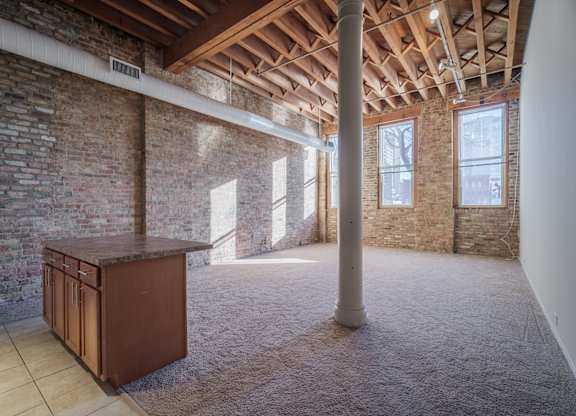 A room with a brick wall and a wooden beam ceiling.