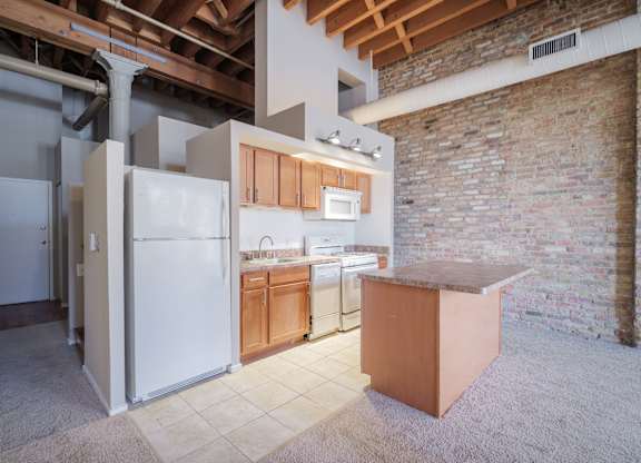 A kitchen with a refrigerator, sink, and cabinets.