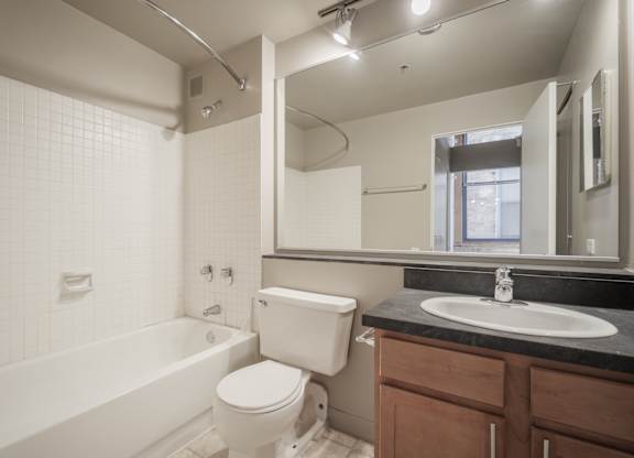 A white toilet sits next to a white bathtub in a bathroom.