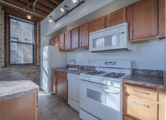 A kitchen with a white stove top oven and wooden cabinets.
