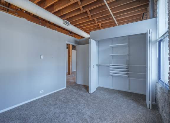 A room with a white wall and a white closet with shelves.
