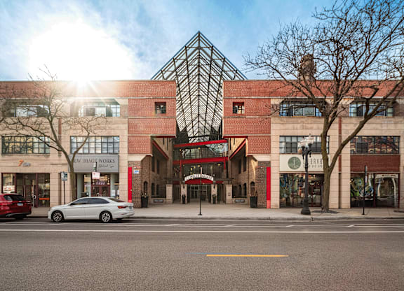 A street view of a building with a red car parked in front.