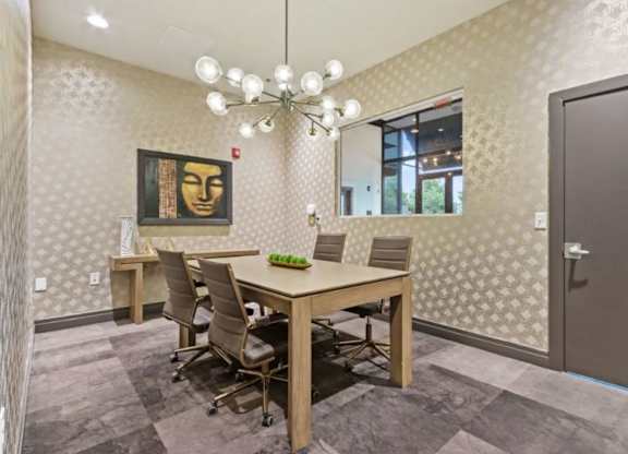A conference room with a table, chairs, and a painting on the wall.