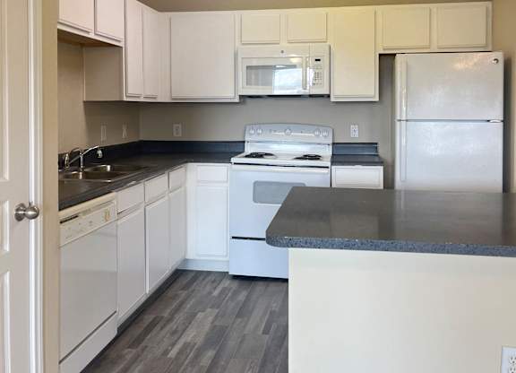 A kitchen with white cabinets and a black countertop.
