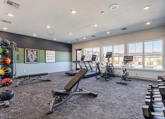 A gym with a variety of equipment including treadmills, weights, and exercise machines.