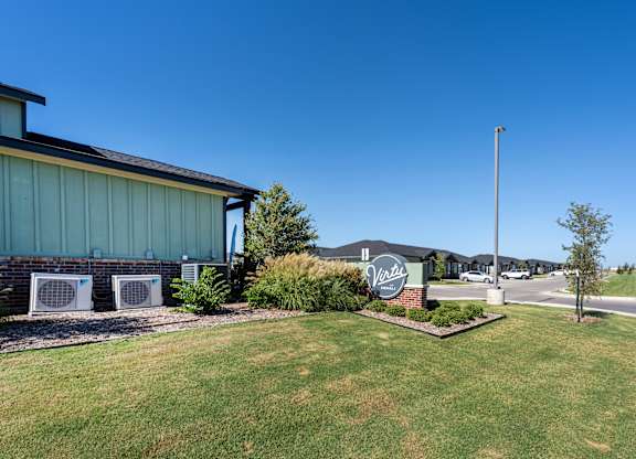 A green lawn in front of a building with a sign that says