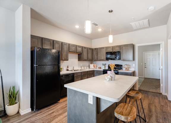 A kitchen with a black fridge and wooden cabinets.