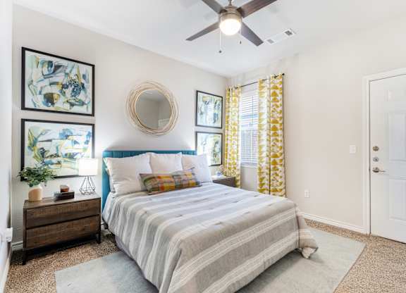 A bedroom with a bed, dresser, mirror, and artwork.