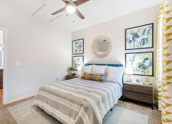 A bedroom with a bed, nightstand, and a ceiling fan.
