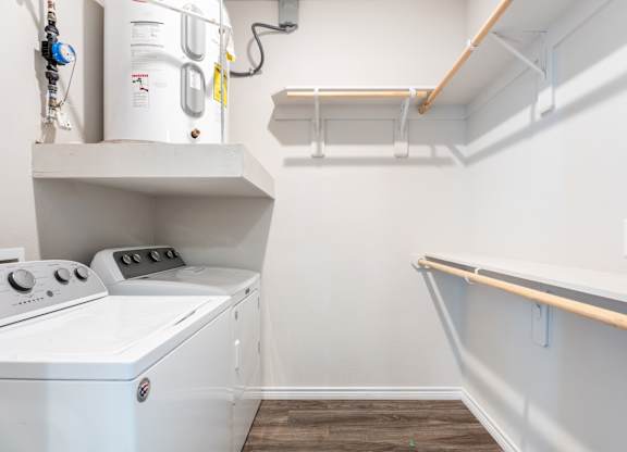 A white washing machine is sitting in a small laundry room.
