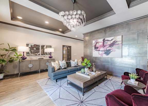 A modern living room with a grey sofa, a coffee table, and a chandelier.