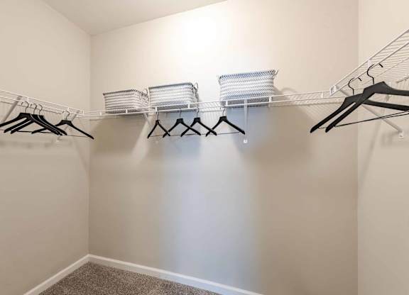 A white closet with clothes hanging on hangers.
