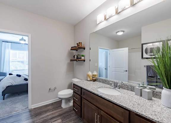 A bathroom with a toilet, sink, and mirror.