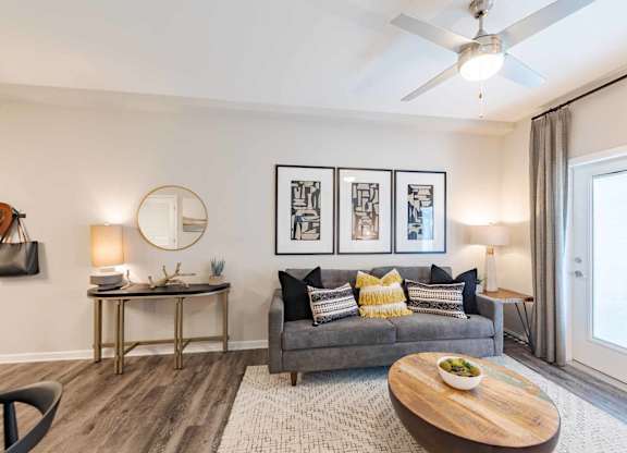 A living room with a grey couch, a coffee table, and a ceiling fan.